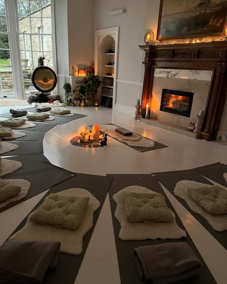 A candlelit retreat room with yoga mats, sheepskin cushions, and a glowing fireplace